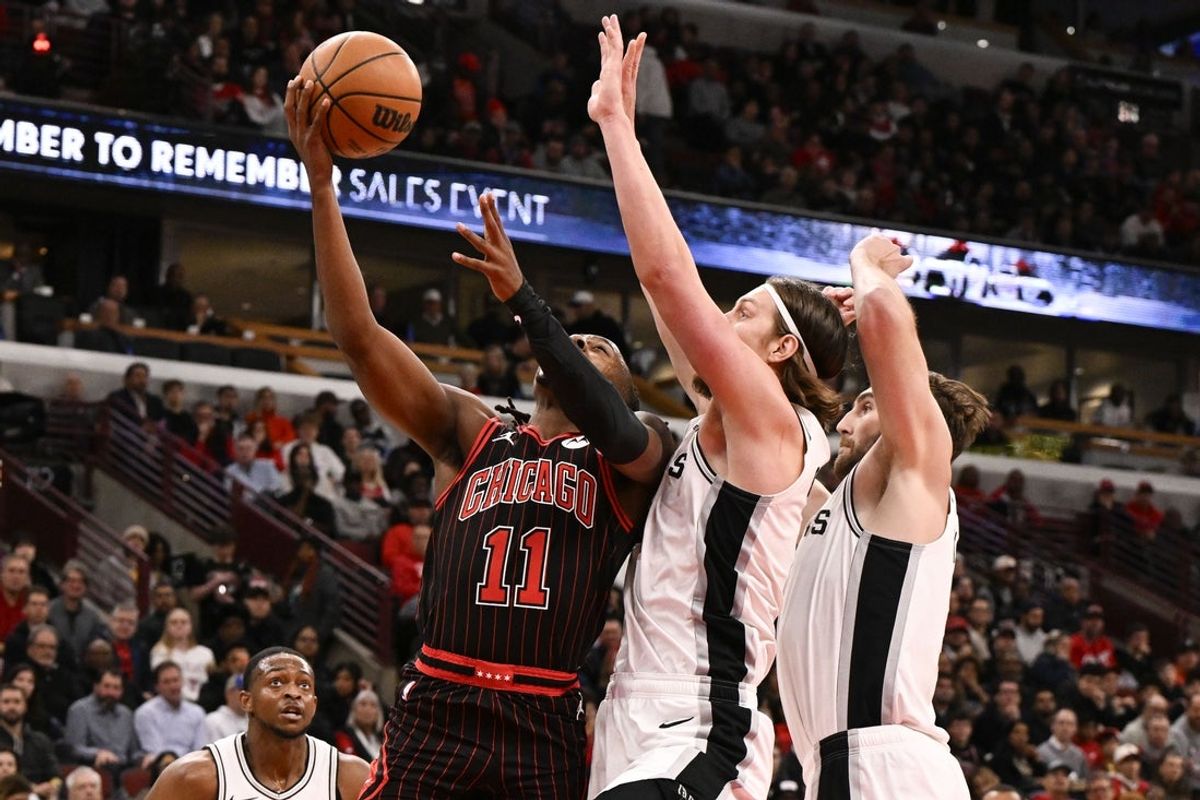 Nov 10, 2025; Chicago, Illinois, USA;  Chicago Bulls guard Ayo Dosunmu (11) shoots against San Antonio Spurs forward Kelly Olynyk (8) and center Luke Kornet (7) during the first half at United Center. Mandatory Credit: Matt Marton-Imagn Images