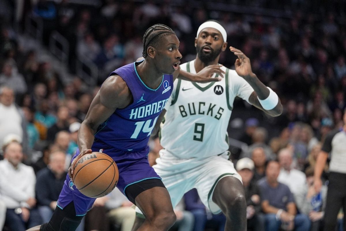 Nov 12, 2025; Charlotte, North Carolina, USA; Charlotte Hornets forward Moussa Diabate (14) looks to pass defended by Milwaukee Bucks forward Bobby Portis (9) during the first quarter at Spectrum Center. Mandatory Credit: Jim Dedmon-Imagn Images