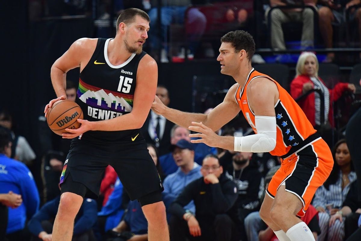 Nov 12, 2025; Inglewood, California, USA; Denver Nuggets center Nikola Jokic (15) moves the ball against Los Angeles Clippers center Brook Lopez (11) during the first half at Intuit Dome. Mandatory Credit: Gary A. Vasquez-Imagn Images