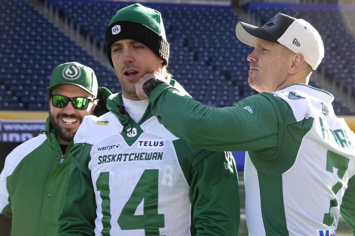 Nov 15, 2025; Winnipeg, Manitoba, Canada; Saskatchewan Roughriders quarterback Trevor Harris (7) playfully punches quarterback Jack Coan (14) as offensive coordinator Marc Mueller looks on during the walk through before the 112th Grey Cup at Princess Auto Stadium. Mandatory Credit: John E. Sokolowski-Imagn Images