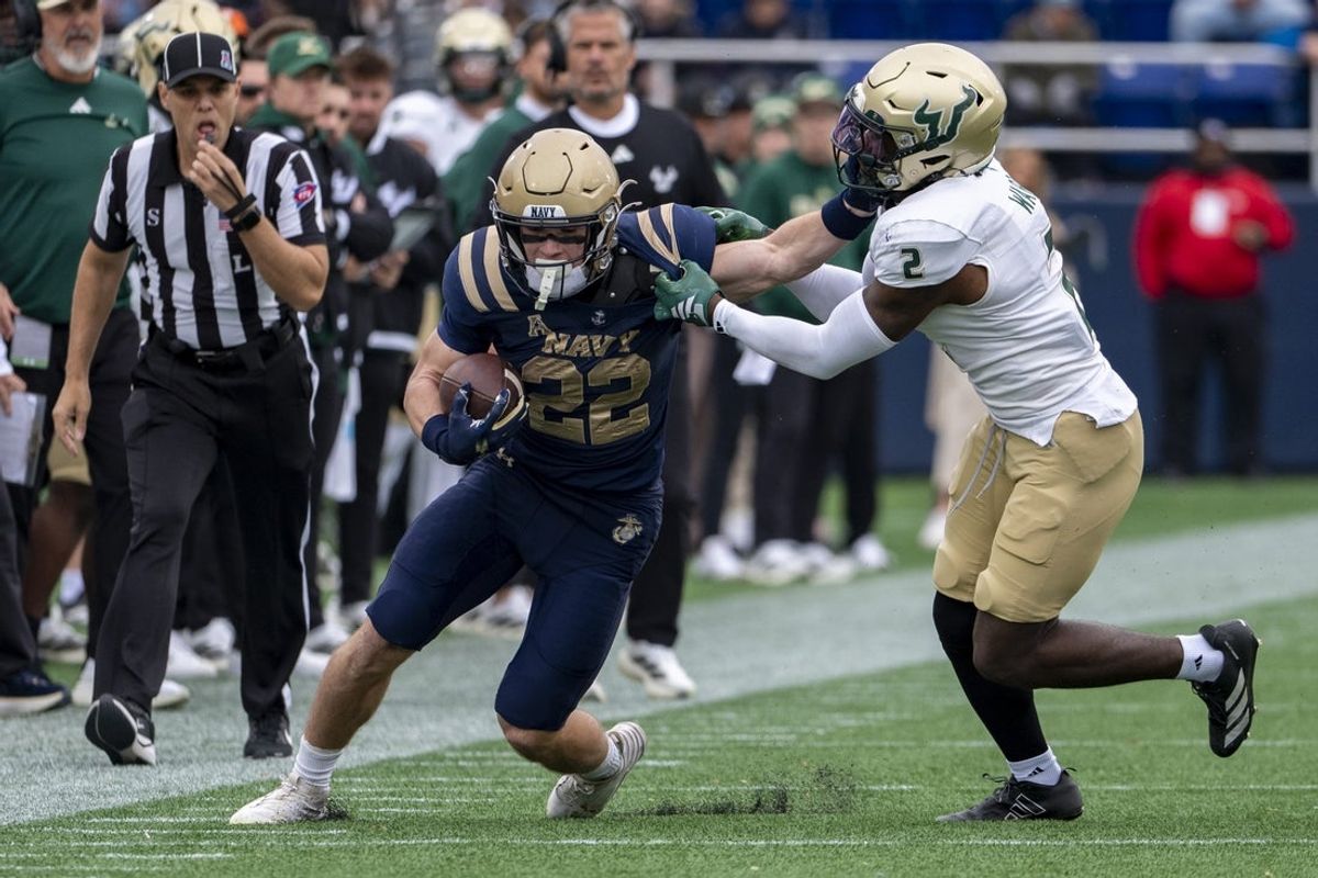Nov 15, 2025; Annapolis, Maryland, USA; Navy Midshipmen running back Eli Heidenreich (22) stiff arms South Florida Bulls cornerback Tavin Ward (2) during the first half  at Navy-Marine Corps Memorial Stadium. Mandatory Credit: Tommy Gilligan-Imagn Images