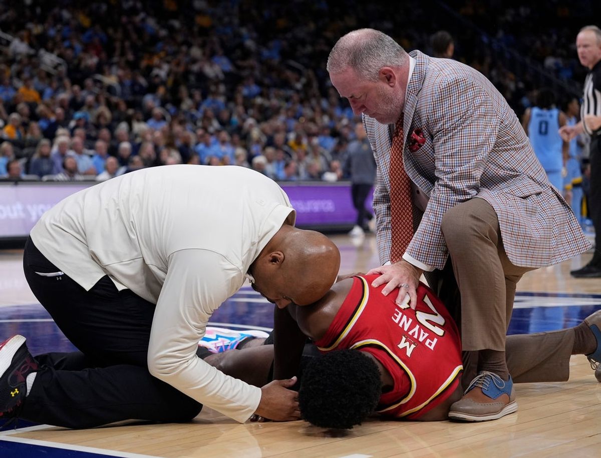Maryland Terrapins head coach Buzz Williams and trainer Eddie Benion attend to Maryland Terrapins forward Pharrel Payne (21) during the second half of the game against the Marquette Golden Eagles on Saturday November 15, 2025 at Fiserv Forum in Milwaukee, Wisconsin.