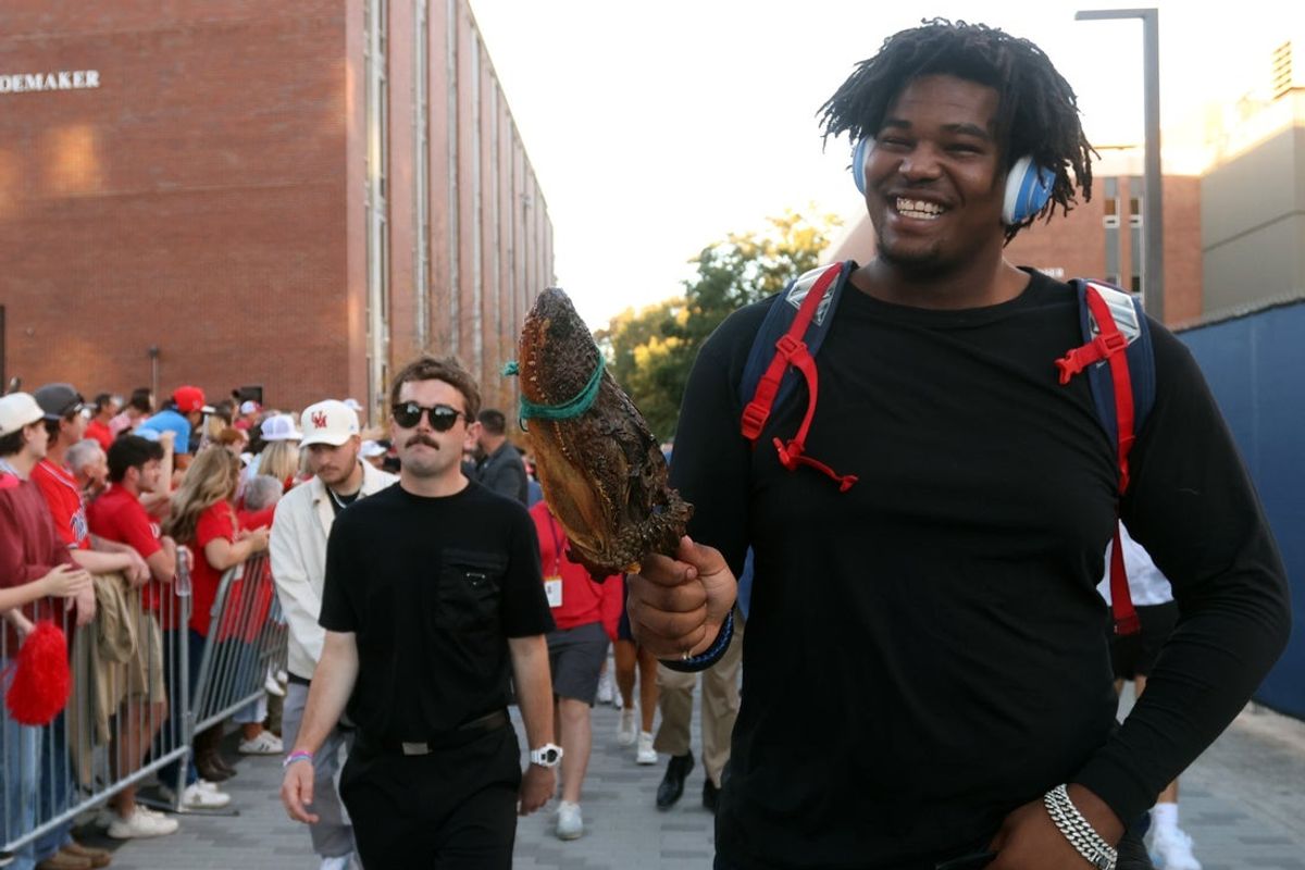 Nov 15, 2025; Oxford, Mississippi, USA; Mississippi Rebels defensive lineman Zxavian Harris (51) carries an alligator from a fan as he makes his way down the Walk of Champions to Vaught-Hemingway Stadium prior to the game against the Florida Gators.  Mandatory Credit: Petre Thomas-Imagn Images
