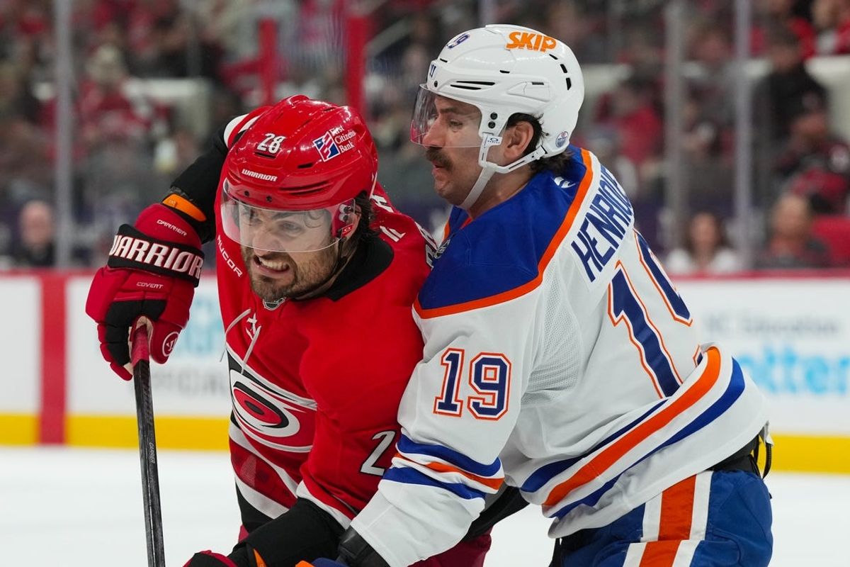 Nov 15, 2025; Raleigh, North Carolina, USA;  Carolina Hurricanes left wing William Carrier (28) and Edmonton Oilers center Adam Henrique (19) battle for position during the first period at Lenovo Center. Mandatory Credit: James Guillory-Imagn Images