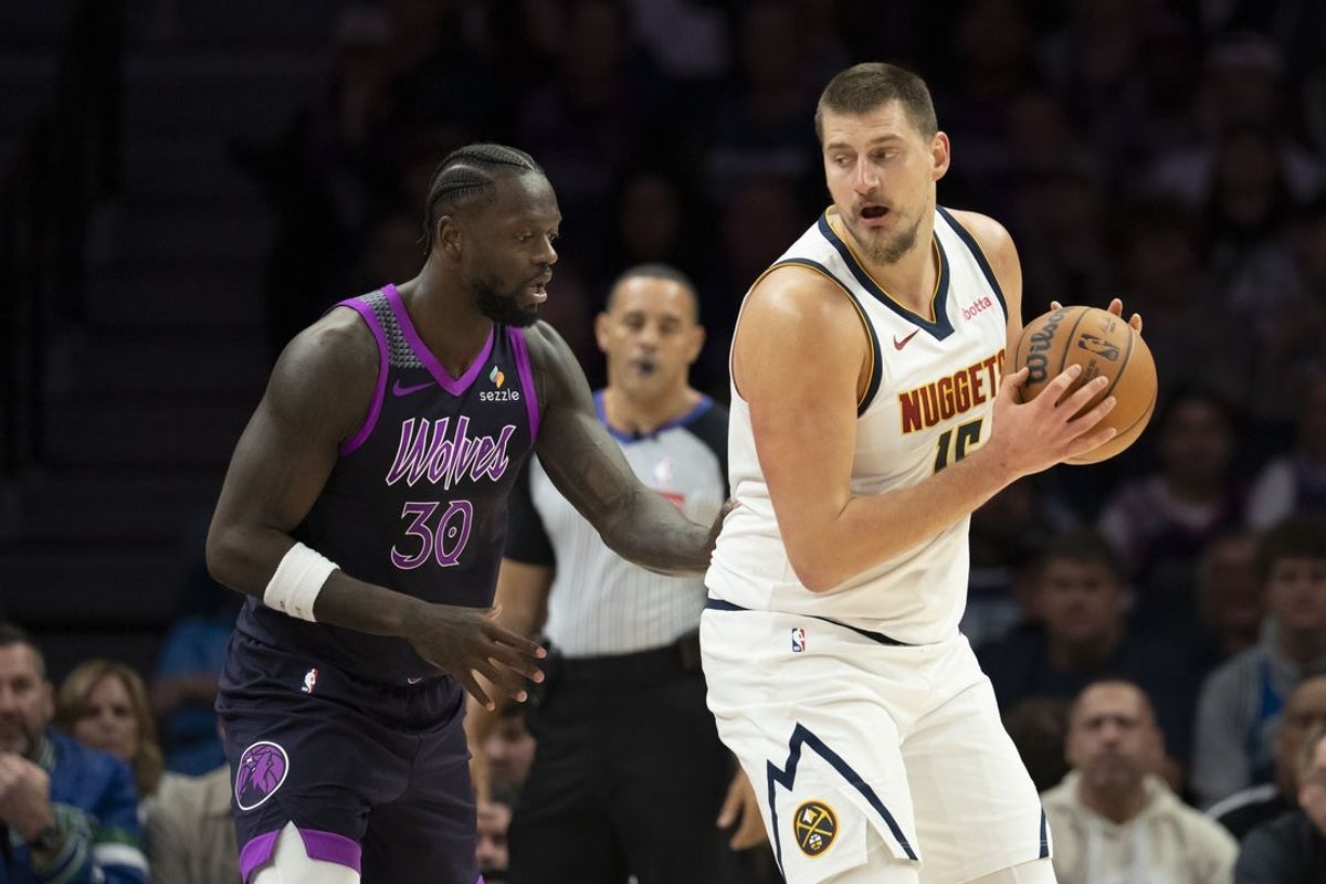 Nov 15, 2025; Minneapolis, Minnesota, USA; Denver Nuggets center Nikola Jokic (15) dribbles the ball as Minnesota Timberwolves forward Julius Randle (30) plays defense in the first half at Target Center. Mandatory Credit: Jesse Johnson-Imagn Images