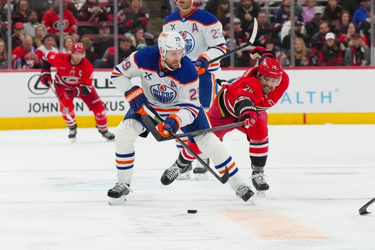 Nov 15, 2025; Raleigh, North Carolina, USA;  Edmonton Oilers center Leon Draisaitl (29) skates with the puck past Carolina Hurricanes left wing William Carrier (28) during the second period at Lenovo Center. Mandatory Credit: James Guillory-Imagn Images