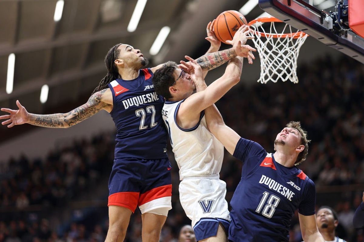 Nov 15, 2025; Villanova, Pennsylvania, USA; Villanova Wildcats center Braden Pierce (17) drives against Duquesne Dukes guard Maximus Edwards (22) and center Stef van Bussel (18) during the first half at William B. Finneran Pavilion. Mandatory Credit: Bill Streicher-Imagn Images