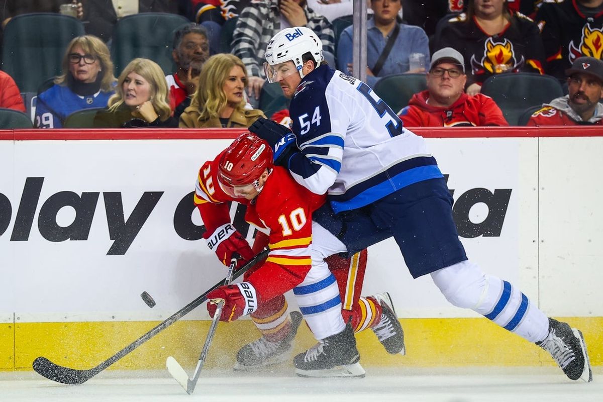 Nov 15, 2025; Calgary, Alberta, CAN; Calgary Flames left wing Jonathan Huberdeau (10) and Winnipeg Jets defenseman Dylan Samberg (54) battle for the puck during the warmup period at Scotiabank Saddledome. Mandatory Credit: Sergei Belski-Imagn Images