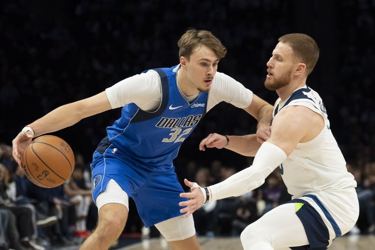 Nov 17, 2025; Minneapolis, Minnesota, USA; Dallas Mavericks forward Cooper Flagg (32) dribbles the ball as Minnesota Timberwolves guard Donte DiVincenzo (0) plays defense in the first half at Target Center. Mandatory Credit: Jesse Johnson-Imagn Images