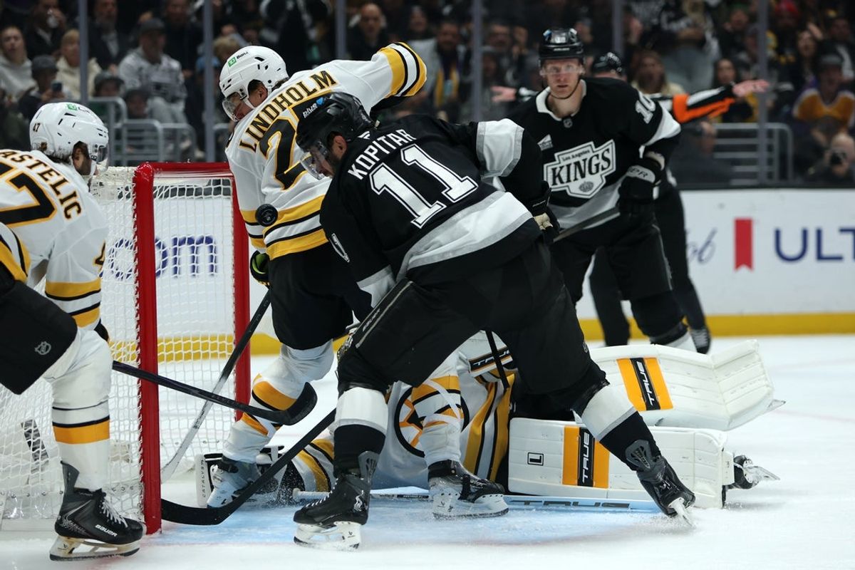 Nov 21, 2025; Los Angeles, California, USA;  Los Angeles Kings center Anze Kopitar (11) fighst for the puck against Boston Bruins defenseman Hampus Lindholm (27) during the second period at Crypto.com Arena. Mandatory Credit: Kiyoshi Mio-Imagn Images