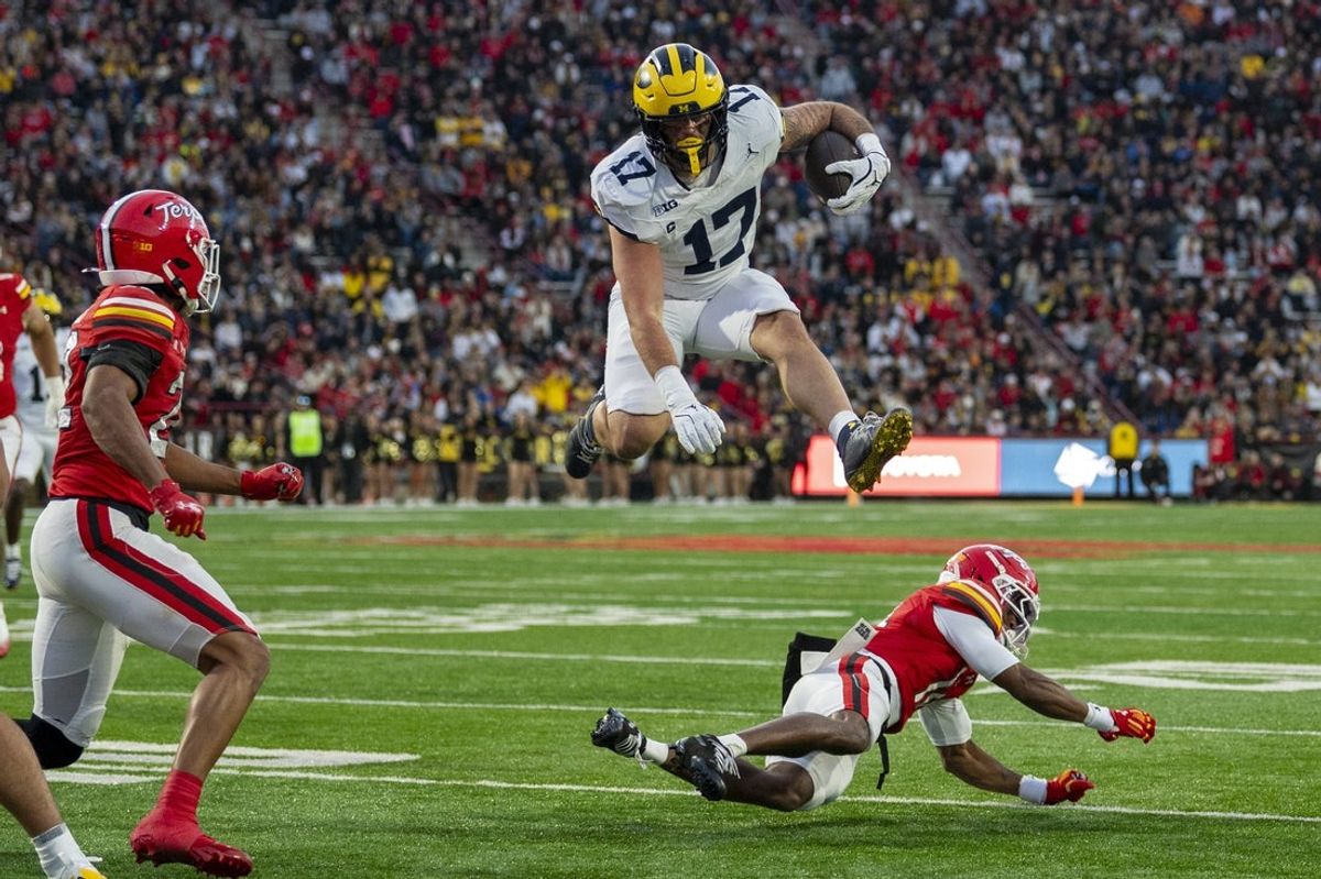 Nov 22, 2025; College Park, Maryland, USA; Michigan Wolverines tight end Marlin Klein (17) leaps Maryland Terrapins defensive back Jamare Glasker (14) during the first half  at SECU Stadium. Mandatory Credit: Tommy Gilligan-Imagn Images