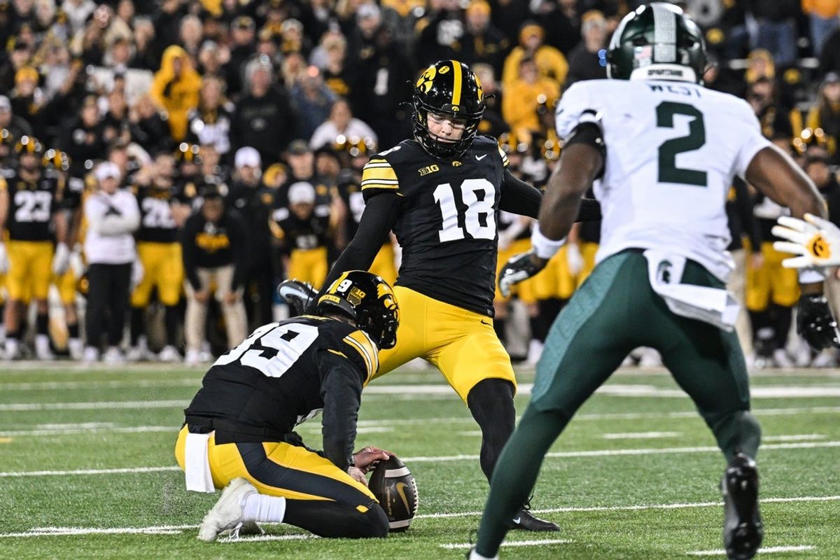 Nov 22, 2025; Iowa City, Iowa, USA; Iowa Hawkeyes kicker Drew Stevens (18) kicks the game winning field goal as punter Ty Nissen (99) holds against the Michigan State Spartans late during the fourth quarter at Kinnick Stadium. Mandatory Credit: Jeffrey Becker-Imagn Images