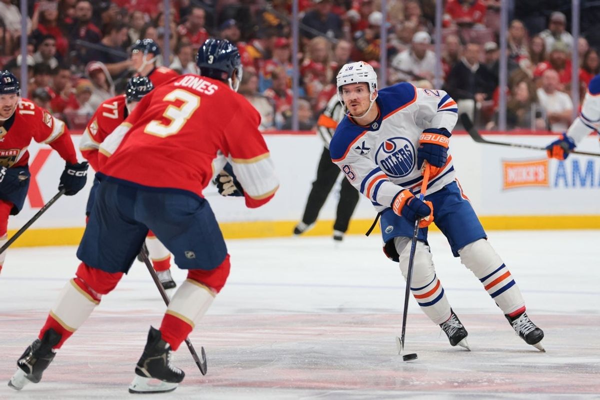 Nov 22, 2025; Sunrise, Florida, USA; Edmonton Oilers center Jack Roslovic (28) moves the puck against Florida Panthers defenseman Seth Jones (3) during the second period at Amerant Bank Arena. Mandatory Credit: Sam Navarro-Imagn Images