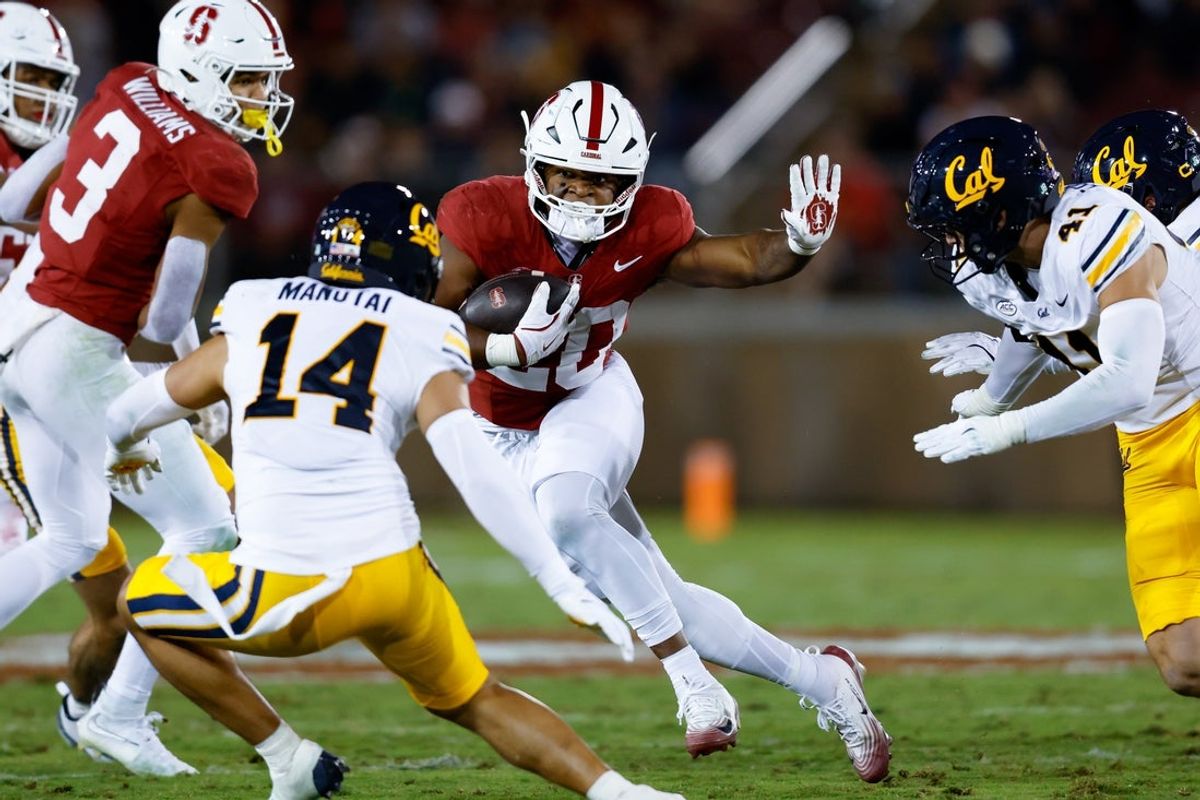Nov 22, 2025; Stanford, California, USA; Stanford Cardinal running back Micah Ford (20) runs past California Golden Bears defensive back Aiden Manutai (14) during the second quarter at Stanford Stadium. Mandatory Credit: Sergio Estrada-Imagn Images