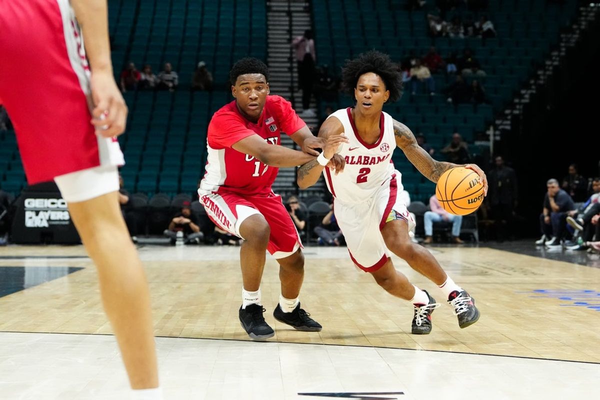Nov 25, 2025; Las Vegas, Nevada, USA; Alabama Crimson Tide guard Aden Holloway (2) drives the ball past UNLV Rebels guard Issac Williamson (12) in the first half in a 2025 Players Era Festival group play game at MGM Grand Garden Arena. Mandatory Credit: Stephen R. Sylvanie-Imagn Images