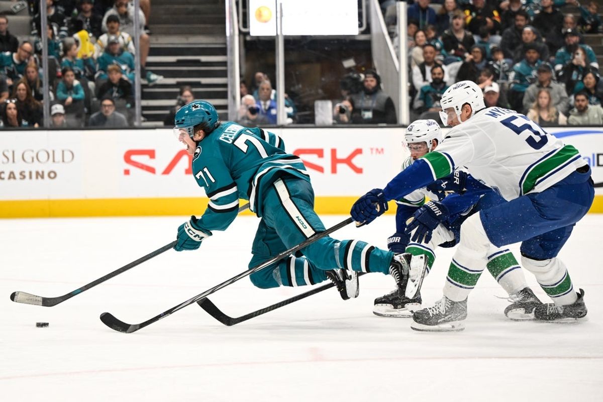 Nov 28, 2025; San Jose, California, USA; San Jose Sharks center Macklin Celebrini (71) get tripped by Vancouver Canucks defenseman Marcus Pettersson (29) while controling the puck against defenseman Tyler Myers (57) in the second period at SAP Center at San Jose. Mandatory Credit: Eakin Howard-Imagn Images