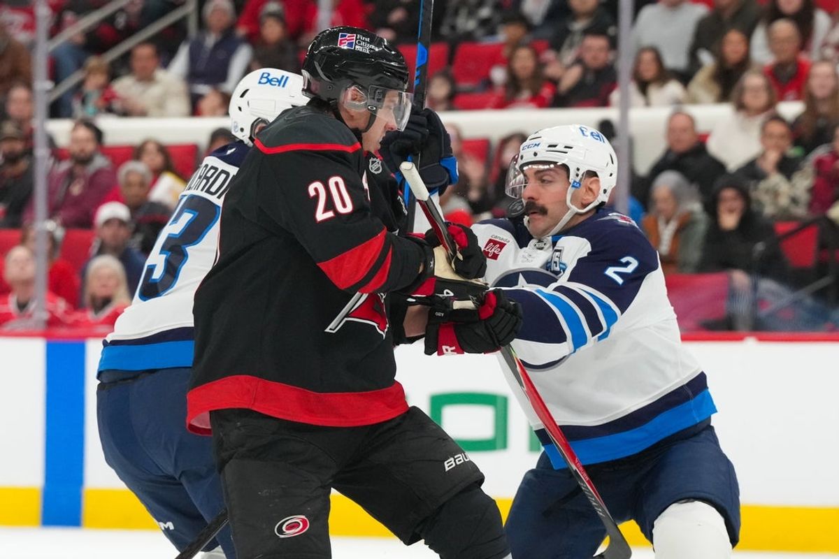 Nov 28, 2025; Raleigh, North Carolina, USA;  Winnipeg Jets defenseman Dylan Demelo (2) and center Gabriel Vilardi (13) check Carolina Hurricanes center Sebastian Aho (20) during the first period at Lenovo Center. Mandatory Credit: James Guillory-Imagn Images