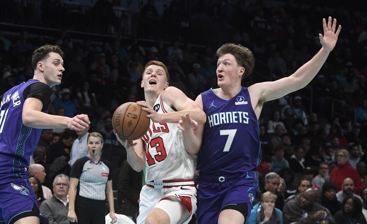 Nov 28, 2025; Charlotte, North Carolina, USA; Chicago Bulls guard Kevin Huerter (13) drives past Charlotte Hornets center Ryan Kalkbrenner (11) and guard Kon Knueppel (7) during the second half at the Spectrum Center. Mandatory Credit: Sam Sharpe-Imagn Images
