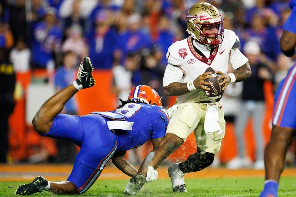 Nov 29, 2025; Gainesville, Florida, USA; Florida State Seminoles quarterback Tommy Castellanos (1) breaks a tackle from Florida Gators linebacker Aaron Chiles (8) during the second half at Ben Hill Griffin Stadium. Mandatory Credit: Matt Pendleton-Imagn Images