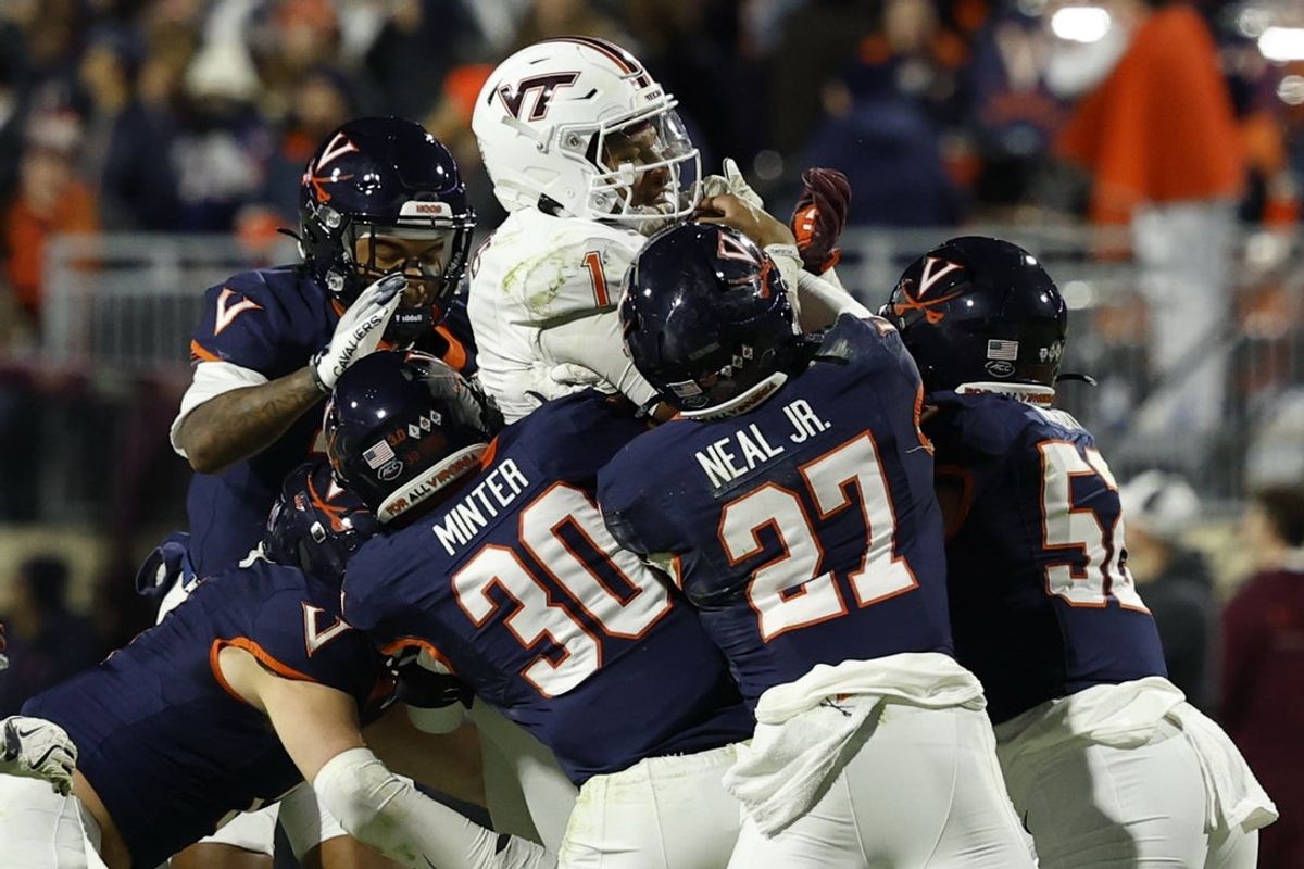 Nov 29, 2025; Charlottesville, Virginia, USA; Virginia Tech Hokies quarterback Kyron Drones (1) is tackled while running the ball on a fourth down by Virginia Cavaliers safety Ethan Minter (30) and Cavaliers safety Devin Neal (27) in the first quarter at Scott Stadium. Mandatory Credit: Geoff Burke-Imagn Images