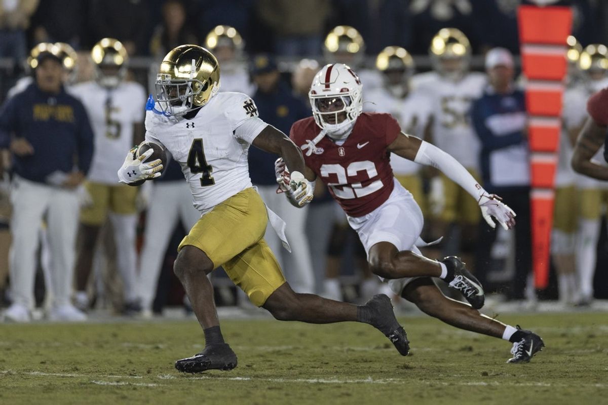 Nov 29, 2025; Stanford, California, USA;  Notre Dame Fighting Irish running back Jeremiyah Love (4) runs with the football during the first quarter against Stanford Cardinal safety Che Ojarikre (22) at Stanford Stadium. Mandatory Credit: Stan Szeto-Imagn Images