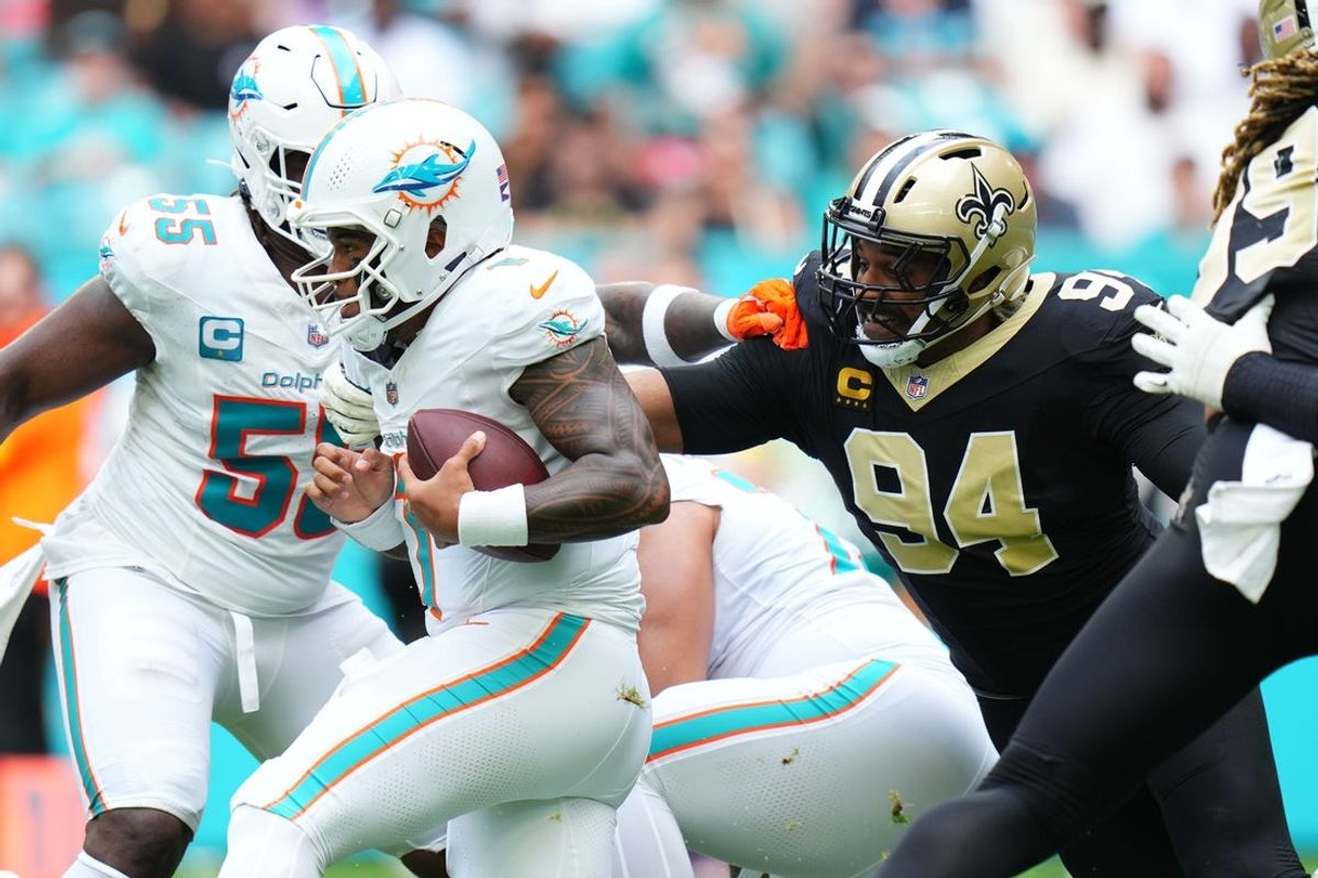Nov 30, 2025; Miami Gardens, Florida, USA; Miami Dolphins quarterback Tua Tagovailoa (1) is pressured by New Orleans Saints defensive end Cameron Jordan (94) during the first half at Hard Rock Stadium. Mandatory Credit: Rich Storry-Imagn Images
