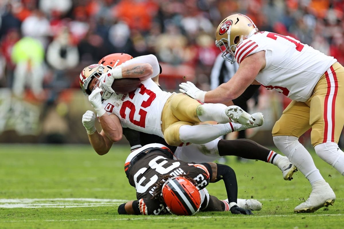 Nov 30, 2025; Cleveland, Ohio, USA;  San Francisco 49ers running back Christian McCaffrey (23) is tackled by Cleveland Browns safety Ronnie Hickman (33) during the first half at Huntington Bank Field. Mandatory Credit: Scott Galvin-Imagn Images