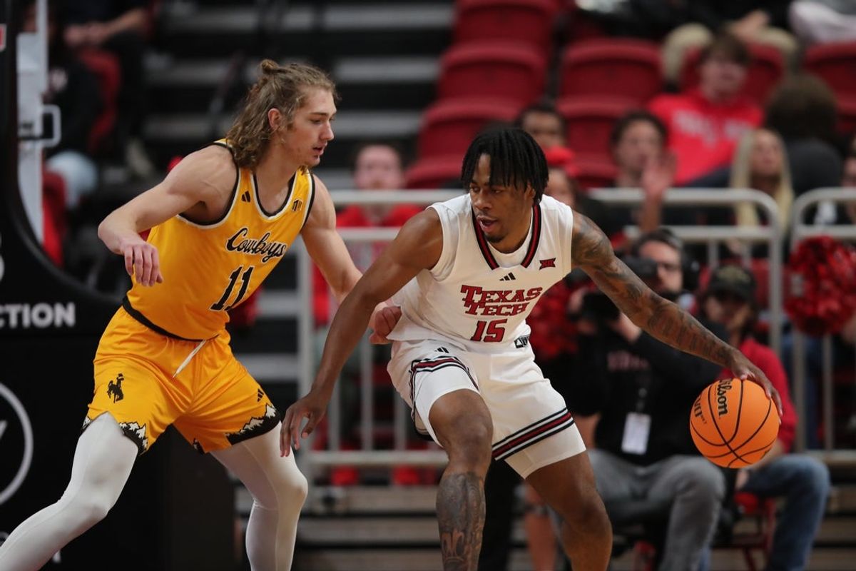 Nov 30, 2025; Lubbock, Texas, USA;  Texas Tech Red Raiders forward JT Toppin (15) dribbles the ball against Wyoming Cowboys guard Adam Gores (11) in the first half  at United Supermarkets Arena. Mandatory Credit: Michael C. Johnson-Imagn Images