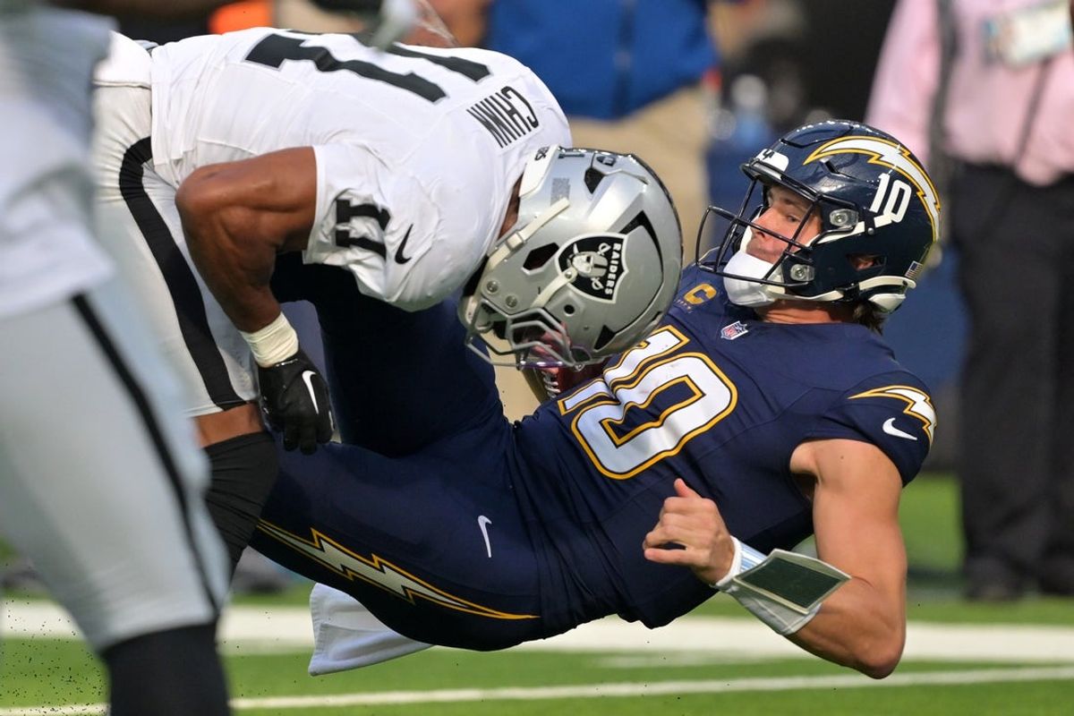Nov 30, 2025; Inglewood, California, USA; Las Vegas Raiders safety Jeremy Chinn (11) tackles Los Angeles Chargers quarterback Justin Herbert (10) during the first half at SoFi Stadium. Mandatory Credit: Jayne Kamin-Oncea-Imagn Images