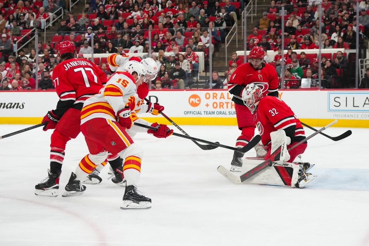 Nov 30, 2025; Raleigh, North Carolina, USA;  Carolina Hurricanes goaltender Brandon Bussi (32) stops the shot by Calgary Flames left wing Dryden Hunt (15) during the second period at Lenovo Center. Mandatory Credit: James Guillory-Imagn Images