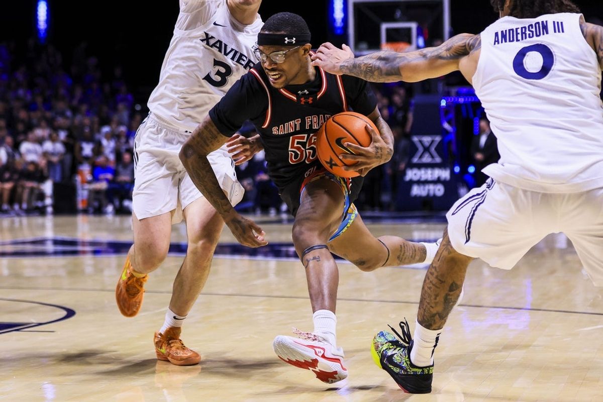 Dec 1, 2025; Cincinnati, Ohio, USA; Saint Francis Red Flash guard Ahmad Harrison (55) drives to the basket against Xavier Musketeers guard Roddie Anderson III (0) in the first half at Cintas Center. Mandatory Credit: Katie Stratman-Imagn Images