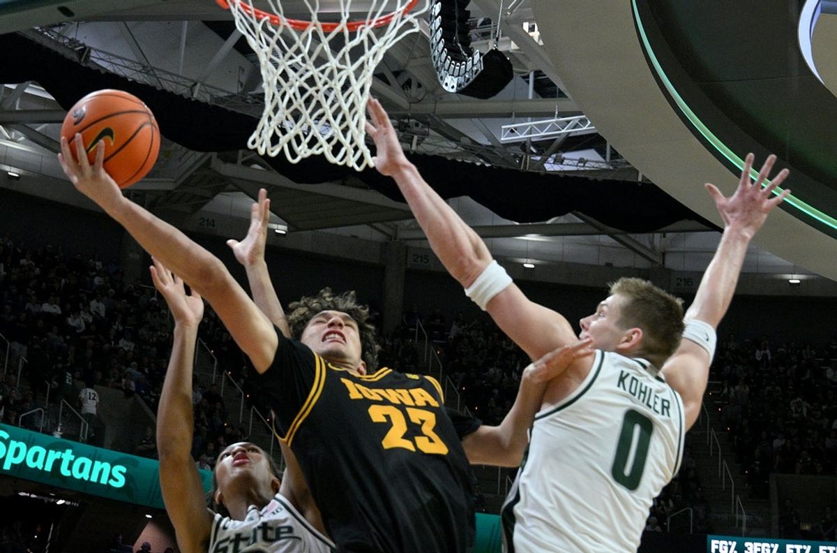 Dec 2, 2025; East Lansing, Michigan, USA;  Iowa Hawkeyes guard Isaia Howard (23) defended by Michigan State Spartans forward Jaxon Kohler (0) during the first half at Jack Breslin Student Events Center. Mandatory Credit: Dale Young-Imagn Images
