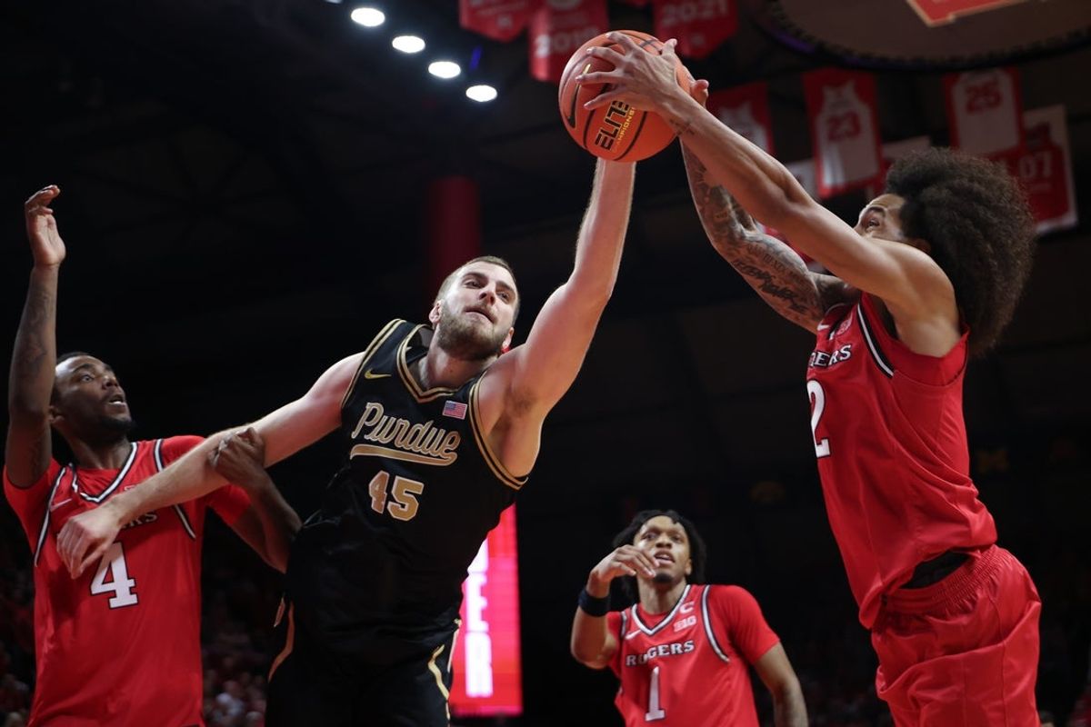Dec 2, 2025; Piscataway, New Jersey, USA; Purdue Boilermakers center Oscar Cluff (45) rebounds against Rutgers Scarlet Knights guard Lino Mark (2) and forward Bryce Dortch (4) during the first half at Jersey Mike's Arena. Mandatory Credit: Vincent Carchietta-Imagn Images