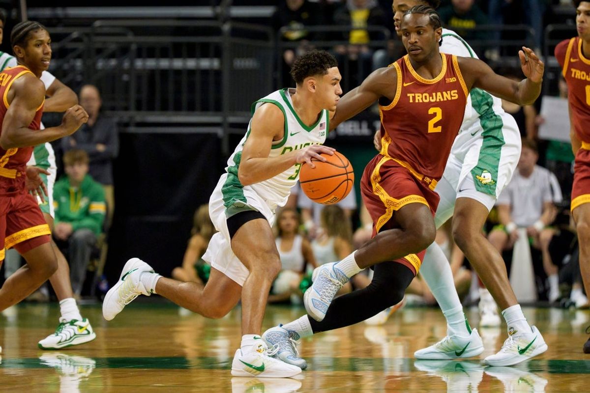 Oregon guard Jackson Shelstad, left, moves the ball under cover from USC forward Ezra Ausar as the Oregon Ducks host the USC Trojans at Matthew Knight Arena in Eugene, Oregon on Dec. 2, 2025.