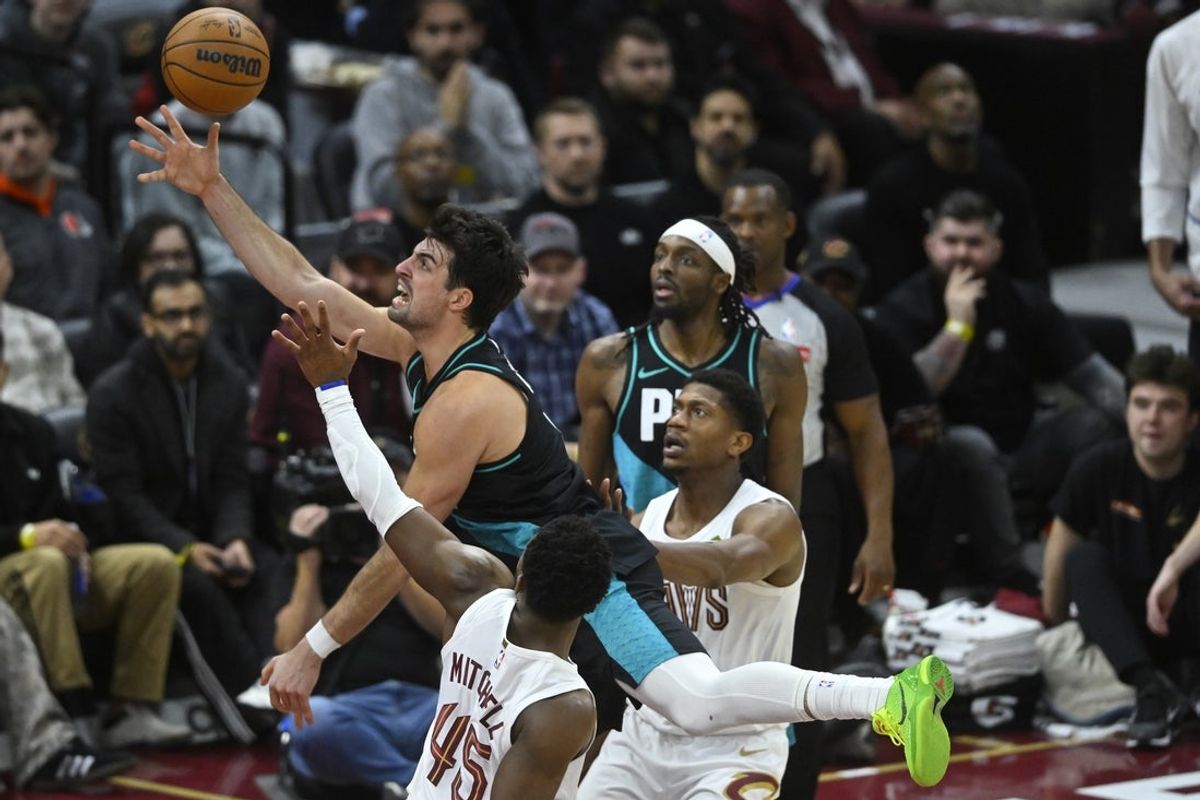 Dec 3, 2025; Cleveland, Ohio, USA; Portland Trail Blazers forward Deni Avdija (8) drives between Cleveland Cavaliers guard Donovan Mitchell (45) and forward De'Andre Hunter (12) in the fourth quarter at Rocket Arena. Mandatory Credit: David Richard-Imagn Images