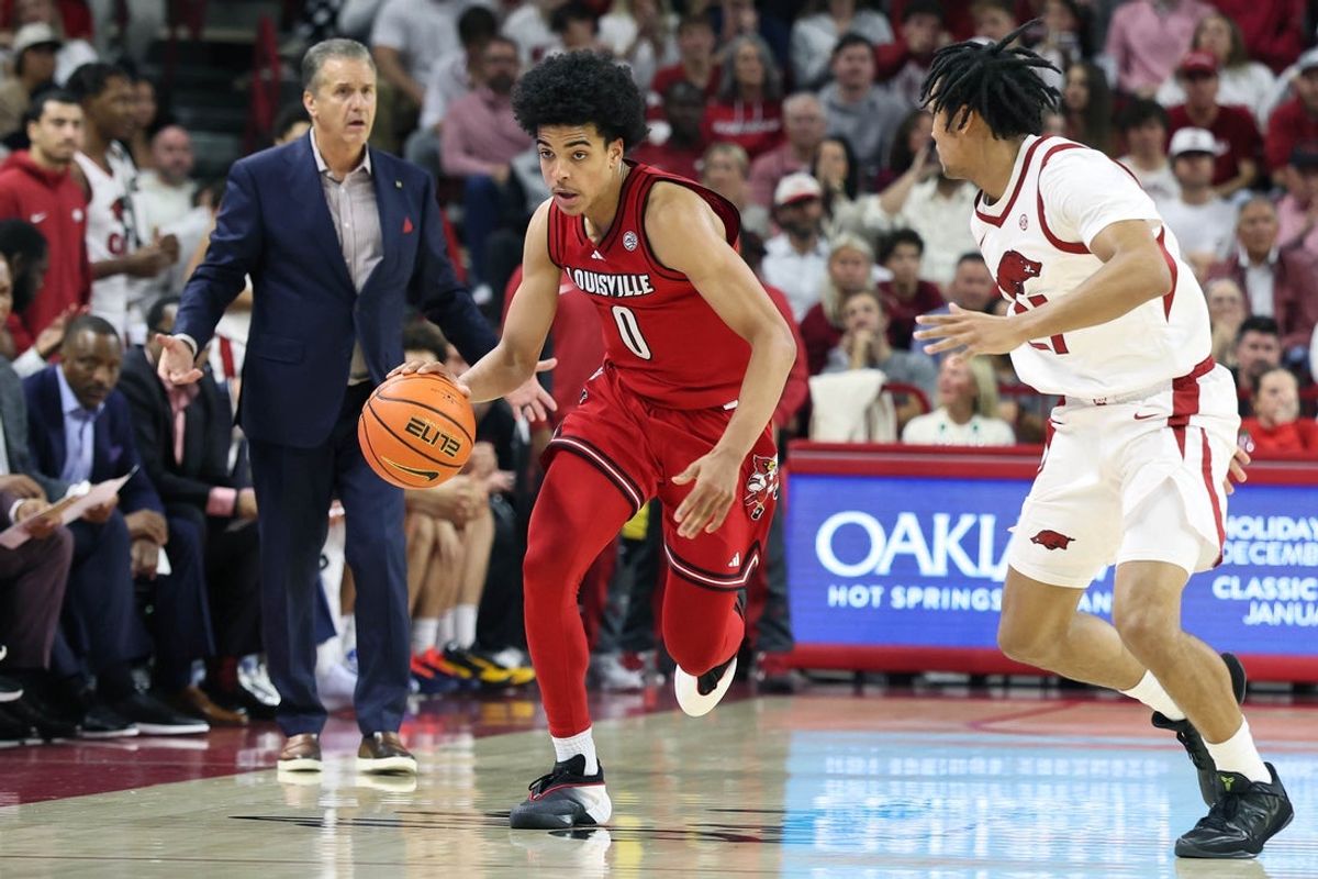 Dec 3, 2025; Fayetteville, Arkansas, USA; Louisville Cardinals guard Mikel Brown Jr (0) drives against Arkansas Razorbacks guard D.J. Wagner (21) as head coach John Calipari watches during the second half at Bud Walton Arena. Arkansas won 89-80. Mandatory Credit: Nelson Chenault-Imagn Images