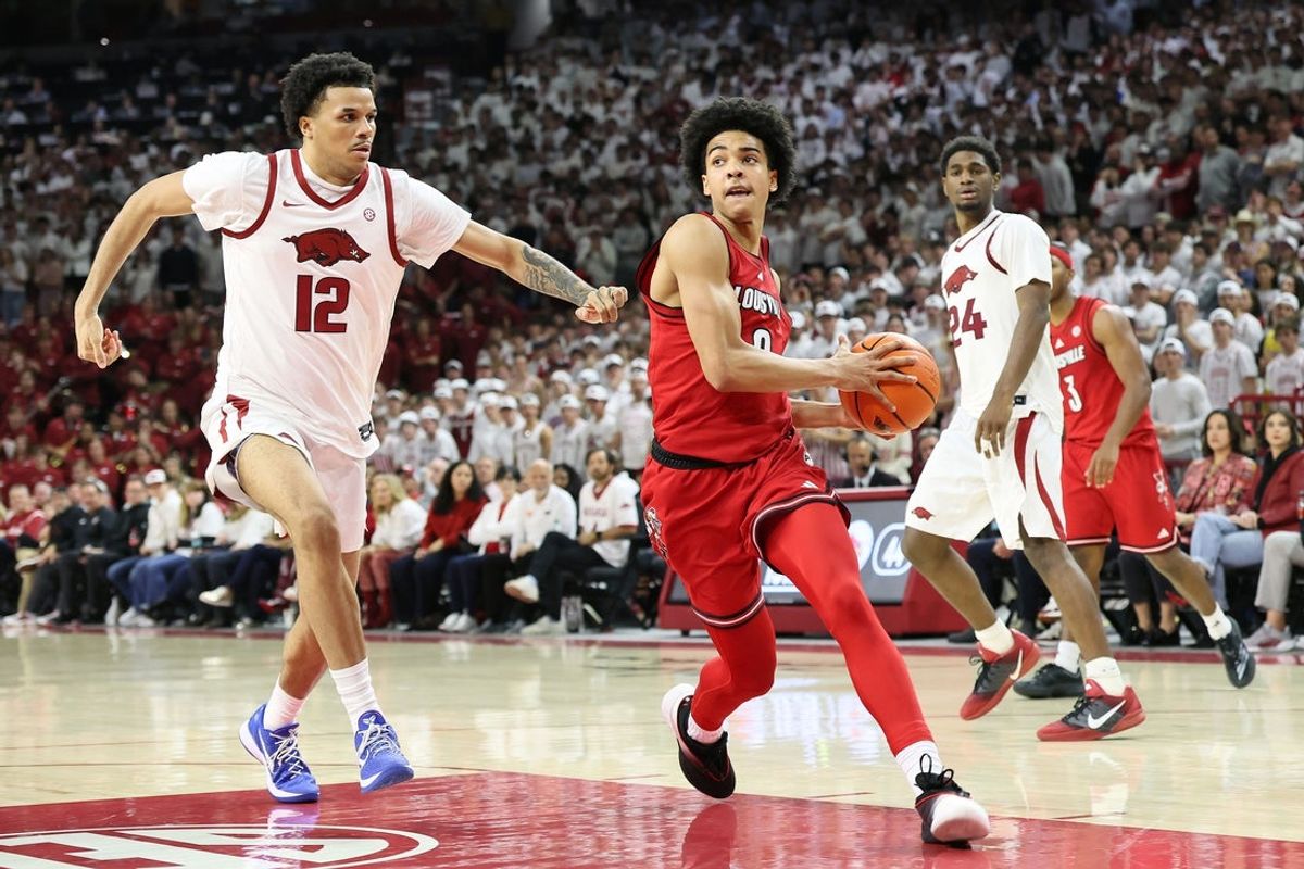Dec 3, 2025; Fayetteville, Arkansas, USA; Louisville Cardinals guard Mikel Brown Jr (0) drives against Arkansas Razorbacks forward Malique Ewin (12) during the second half at Bud Walton Arena. Arkansas won 89-80. Mandatory Credit: Nelson Chenault-Imagn Images