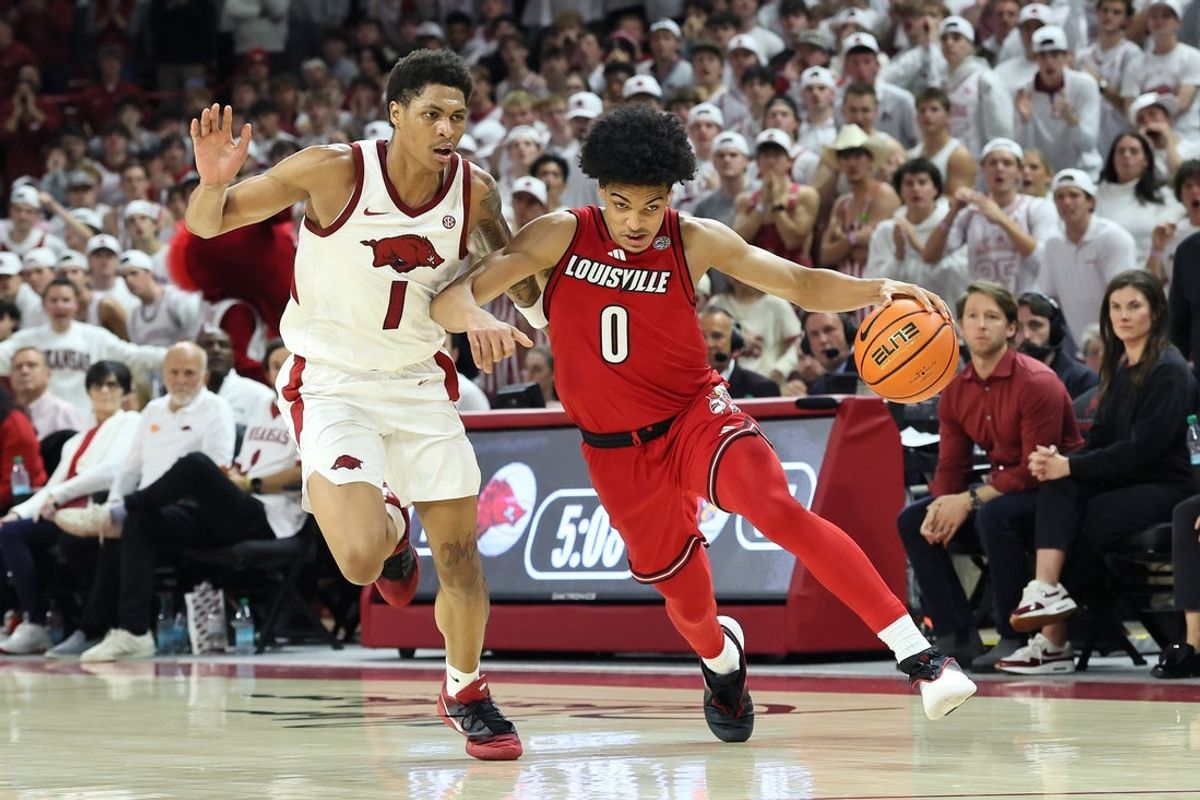 Dec 3, 2025; Fayetteville, Arkansas, USA; Louisville Cardinals guard Mikel Brown Jr (0) dribbles around Arkansas Razorbacks guard Meleek Thomas (1) during the second half at Bud Walton Arena. Arkansas won 89-80. Mandatory Credit: Nelson Chenault-Imagn Images