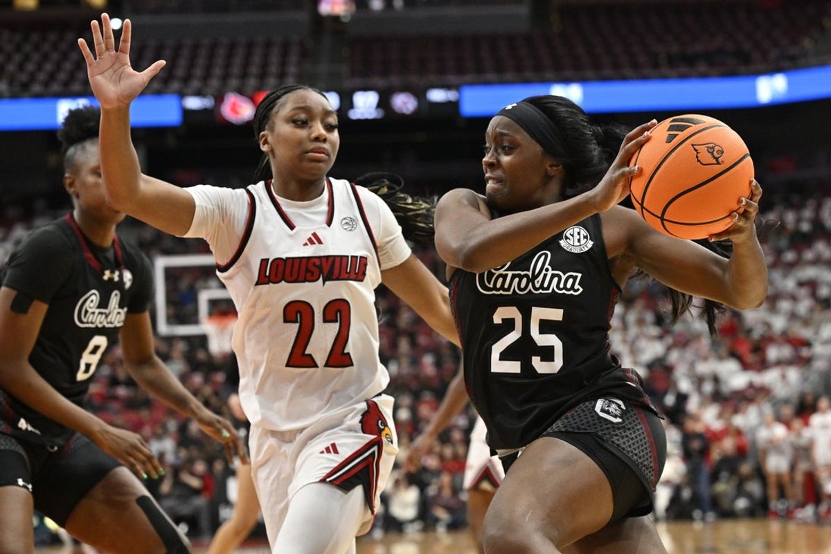 Dec 4, 2025; Louisville, Kentucky, USA; South Carolina Gamecocks guard Raven Johnson (25) drives to the basket against Louisville Cardinals guard Tajianna Roberts (22) during the second half at KFC Yum! Center. South Carolina defeated Louisville 79-77. Mandatory Credit: Jamie Rhodes-Imagn Images