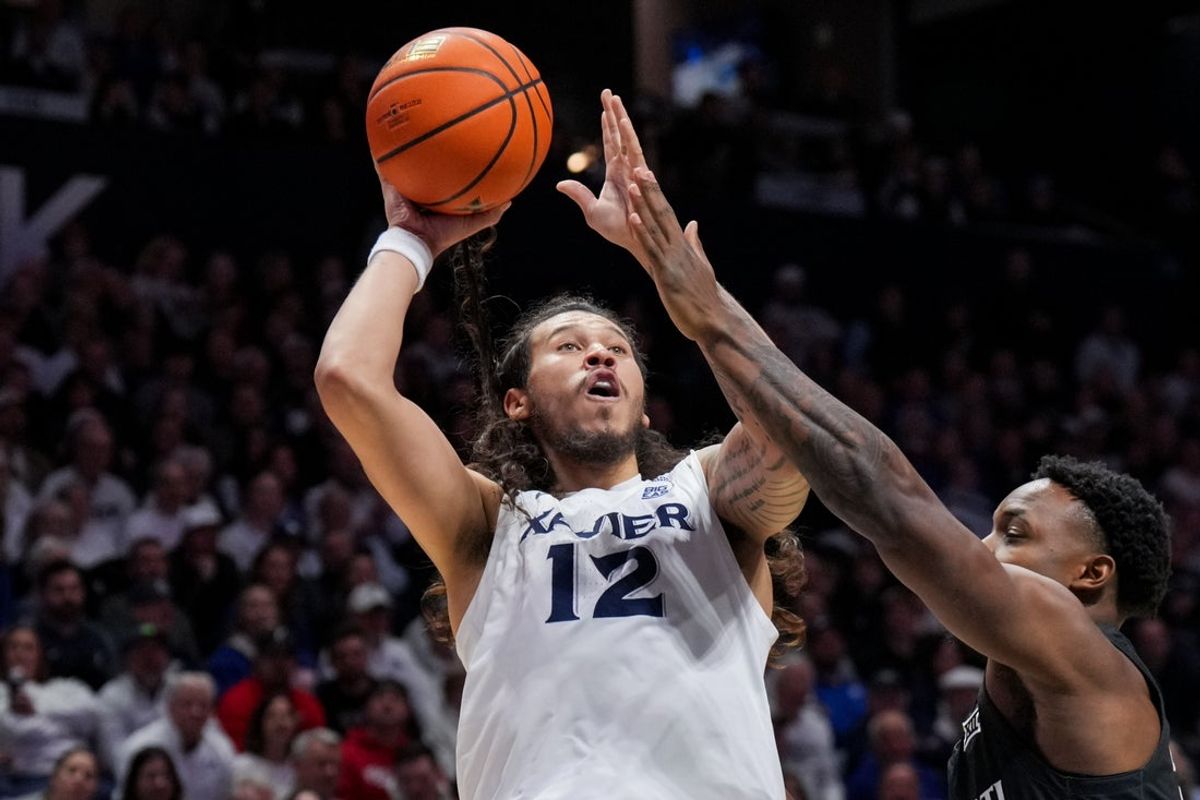 Dec 5, 2025; Cincinnati, Ohio, USA;  Xavier Musketeers forward Tre Carroll (12) drives to the basket against Cincinnati Bearcats forward Jalen Celestine (32) in the first half at the Cintas Center. Mandatory Credit: Aaron Doster-Imagn Images