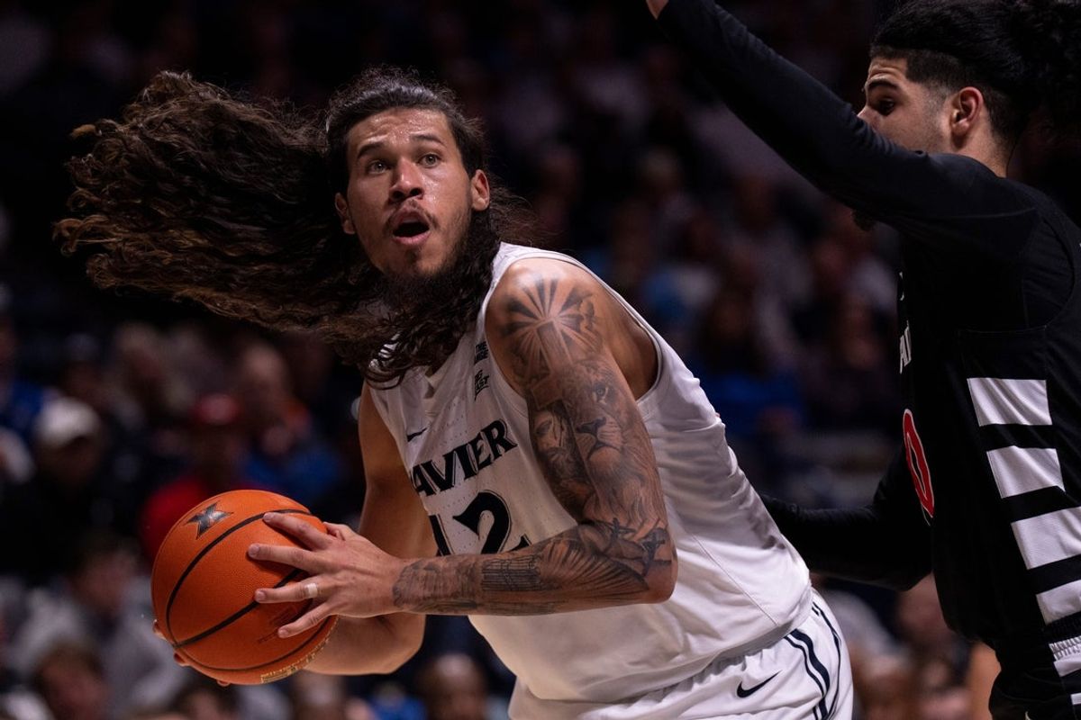 Xavier Musketeers forward Tre Carroll (12) drives on Cincinnati Bearcats guard Shon Abaev (10) in the second half of the NCAA basketball game at the Cintas Center in Cincinnati on Dec. 5, 2025.