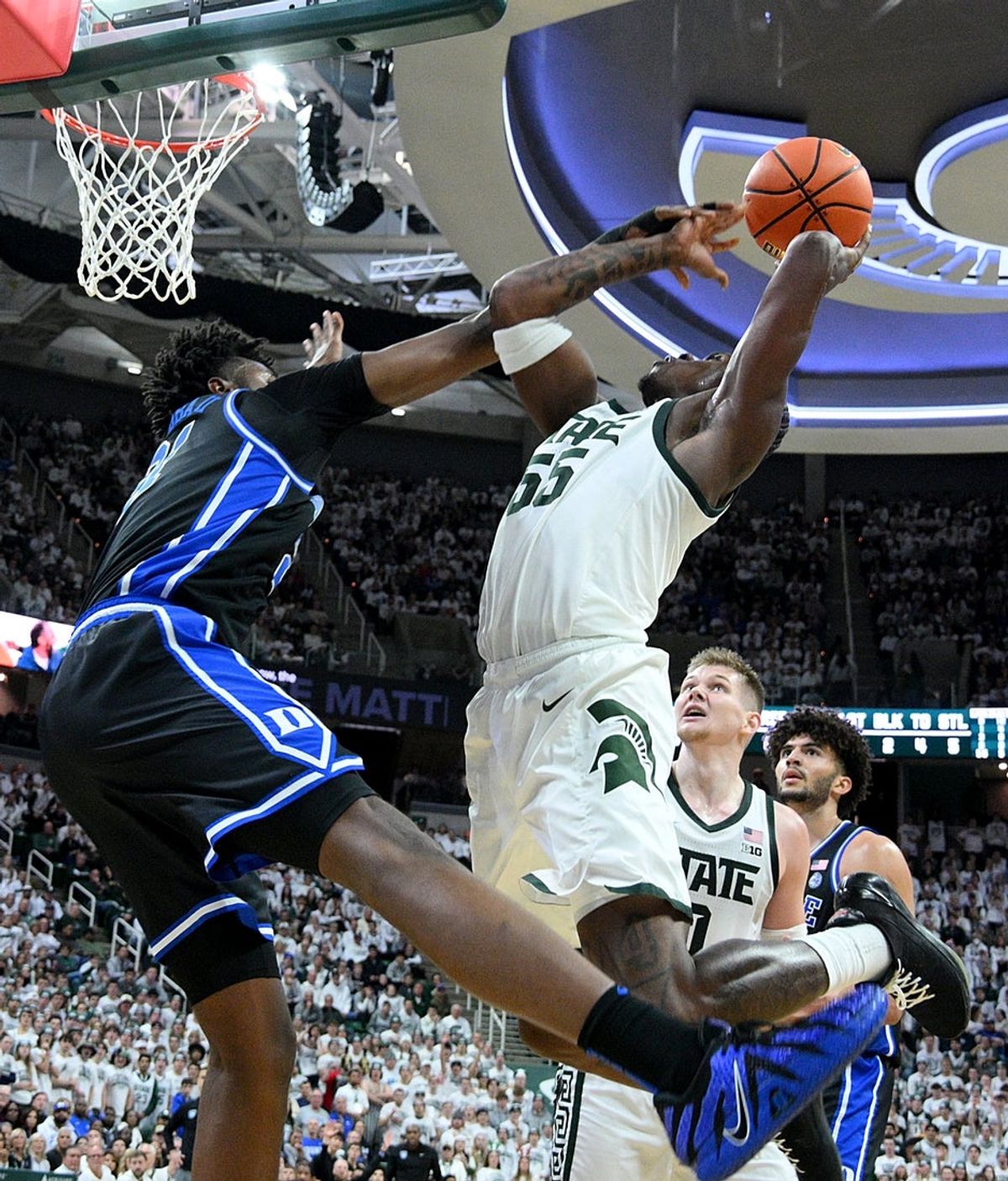 Dec 6, 2025; East Lansing, Michigan, USA;  Duke Blue Devils center Patrick Ngongba (21) fouls Michigan State Spartans forward Coen Carr (55) under the basket during the second half at Jack Breslin Student Events Center. Mandatory Credit: Dale Young-Imagn Images