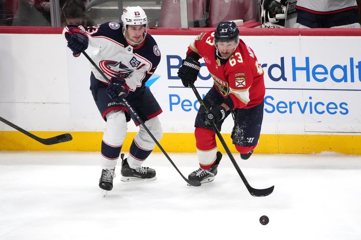 Dec 6, 2025; Sunrise, Florida, USA;  Florida Panthers left wing Brad Marchand (63) and Columbus Blue Jackets center Sean Monahan (23) battle for possession of the puck during the third period at Amerant Bank Arena. Mandatory Credit: Jim Rassol-Imagn Images