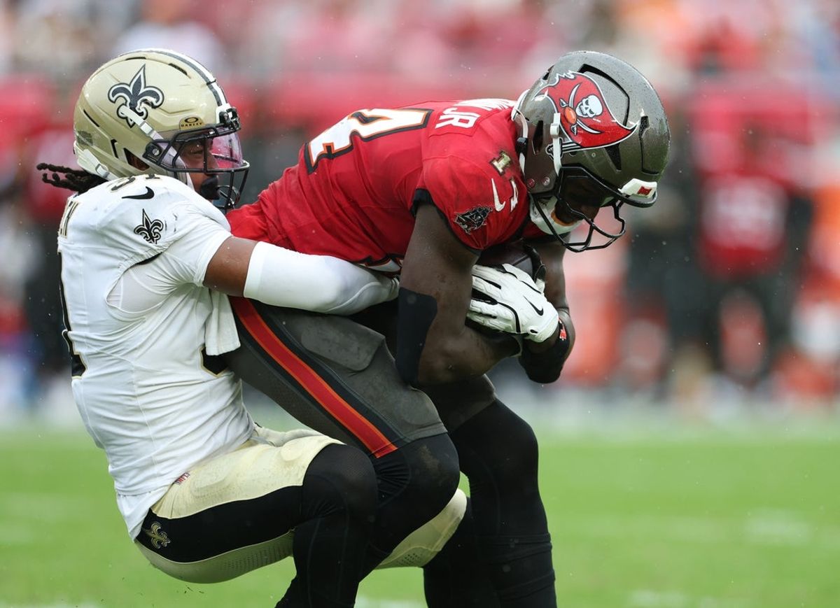 Dec 7, 2025; Tampa, Florida, USA; Tampa Bay Buccaneers wide receiver Chris Godwin Jr. (14) is tackled by New Orleans Saints safety Jordan Howden (31) during the first quarter at Raymond James Stadium. Mandatory Credit: Nathan Ray Seebeck-Imagn Images