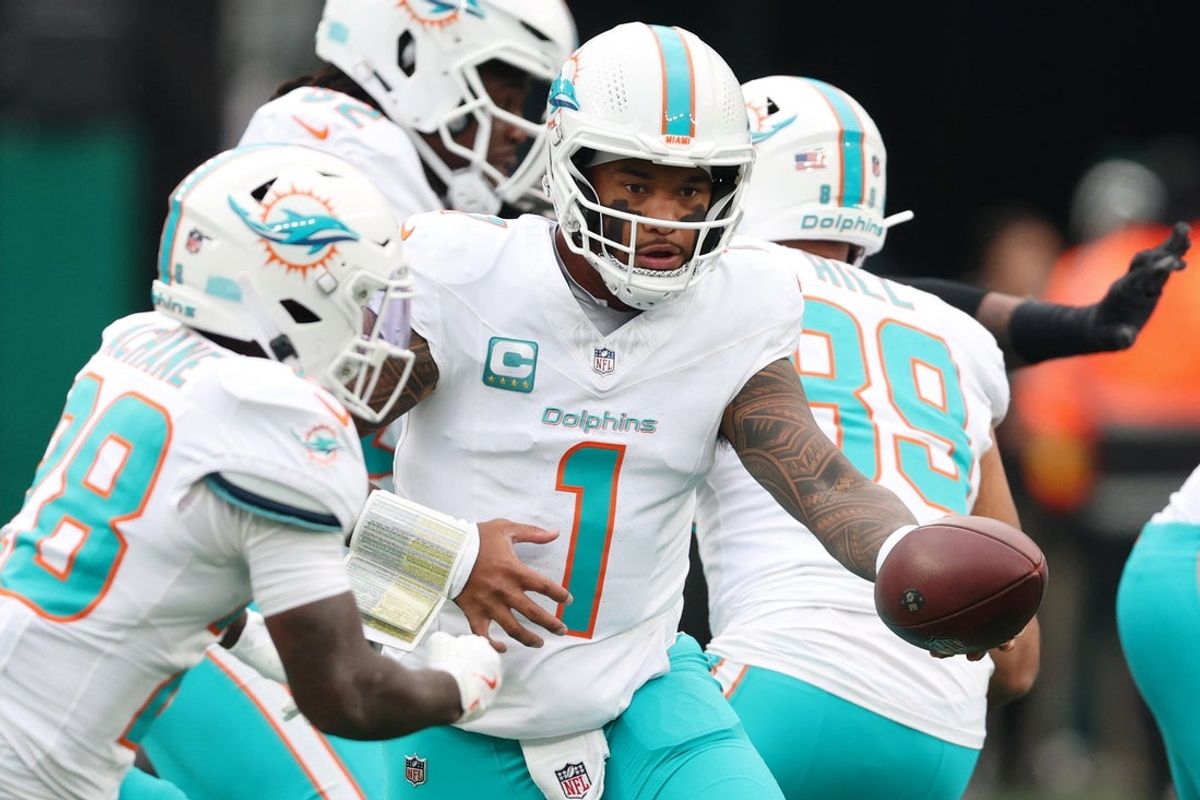 Dec 7, 2025; East Rutherford, New Jersey, USA; Miami Dolphins quarterback Tua Tagovailoa (1) hands off the ball to running back De'Von Achane (28) against the New York Jets during the first half at MetLife Stadium. Mandatory Credit: Vincent Carchietta-Imagn Images