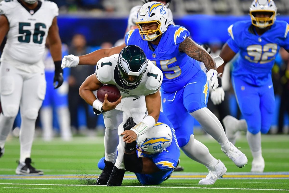 Dec 8, 2025; Inglewood, California, USA; Los Angeles Chargers linebacker Odafe Oweh (98) tackles Philadelphia Eagles quarterback Jalen Hurts (1) in the first half at SoFi Stadium. Mandatory Credit: Gary A. Vasquez-Imagn Images