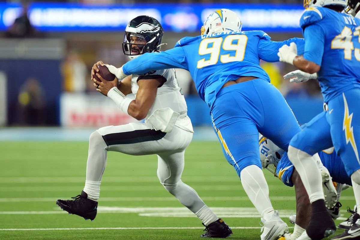 Dec 8, 2025; Inglewood, California, USA; Los Angeles Chargers defensive tackle Jamaree Caldwell (99) tackles Philadelphia Eagles quarterback Jalen Hurts (1) in the first half at SoFi Stadium. Mandatory Credit: Kirby Lee-Imagn Images