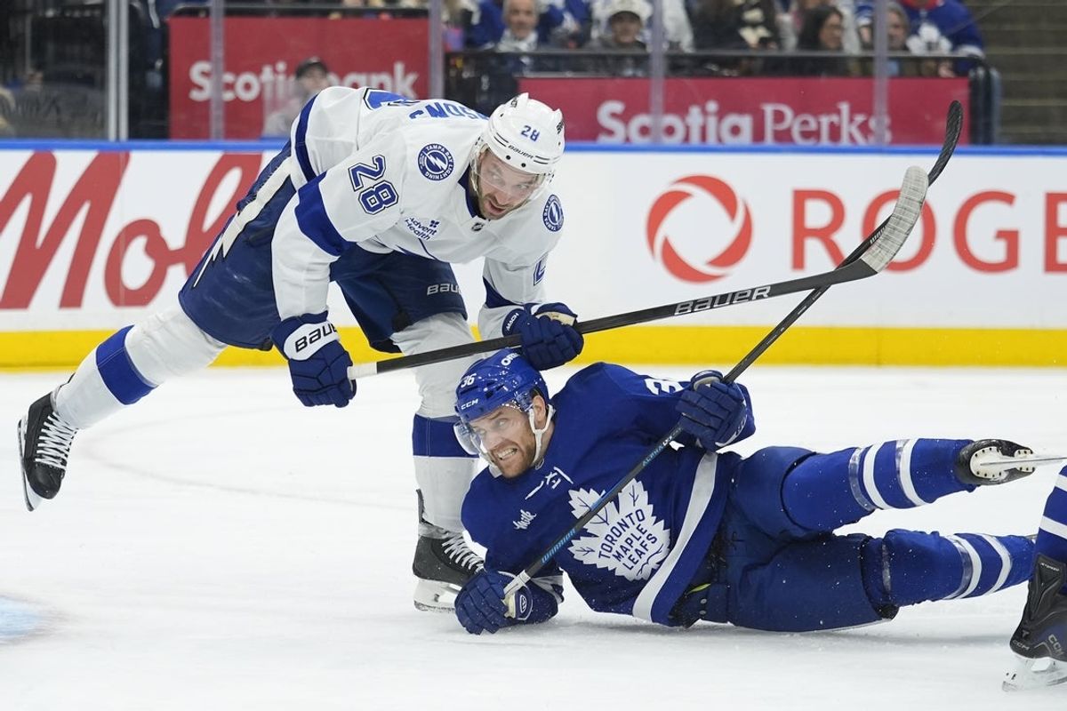 Dec 8, 2025; Toronto, Ontario, CAN; Tampa Bay Lightning forward Zemgus Girgensons (28) knocks Toronto Maple Leafs defenseman Dakots Mermis (36) to the ice during the second period at Scotiabank Arena. Mandatory Credit: John E. Sokolowski-Imagn Images