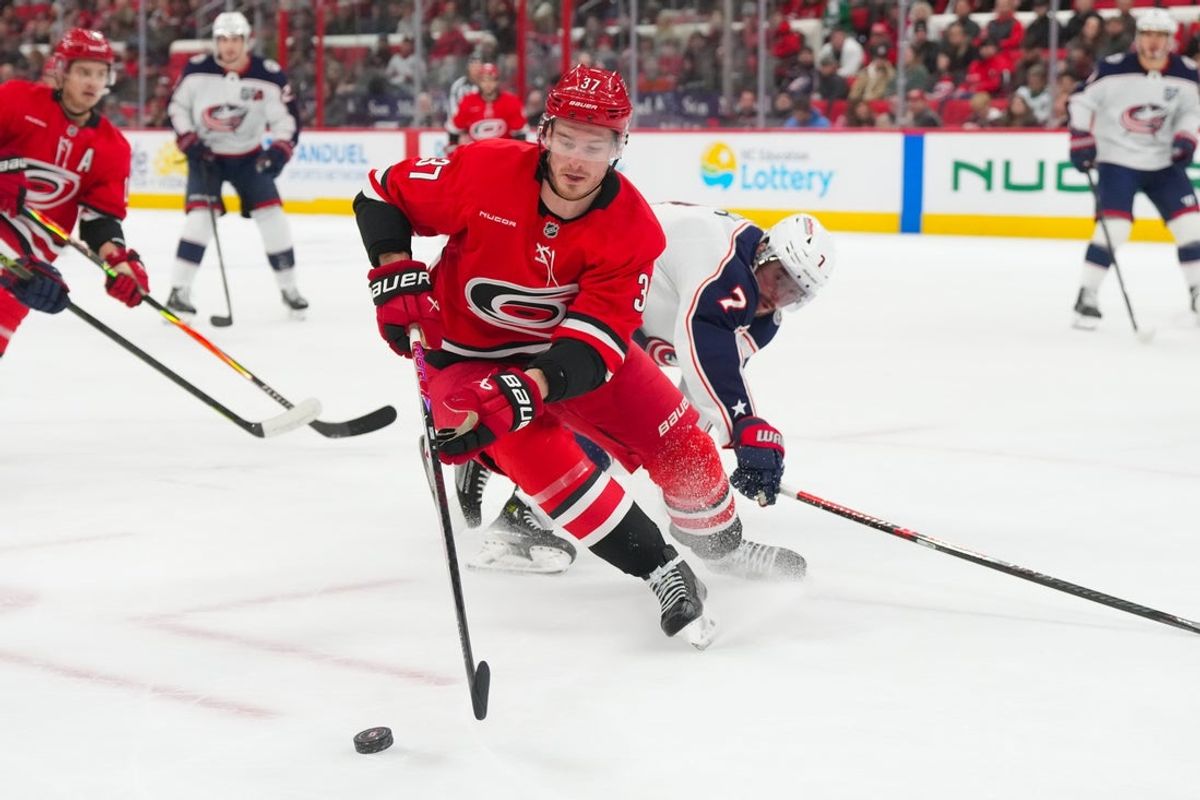 Dec 9, 2025; Raleigh, North Carolina, USA;  Carolina Hurricanes right wing Andrei Svechnikov (37) skates with the puck against Columbus Blue Jackets defenseman Brendan Smith (7) during the first period at Lenovo Center. Mandatory Credit: James Guillory-Imagn Images