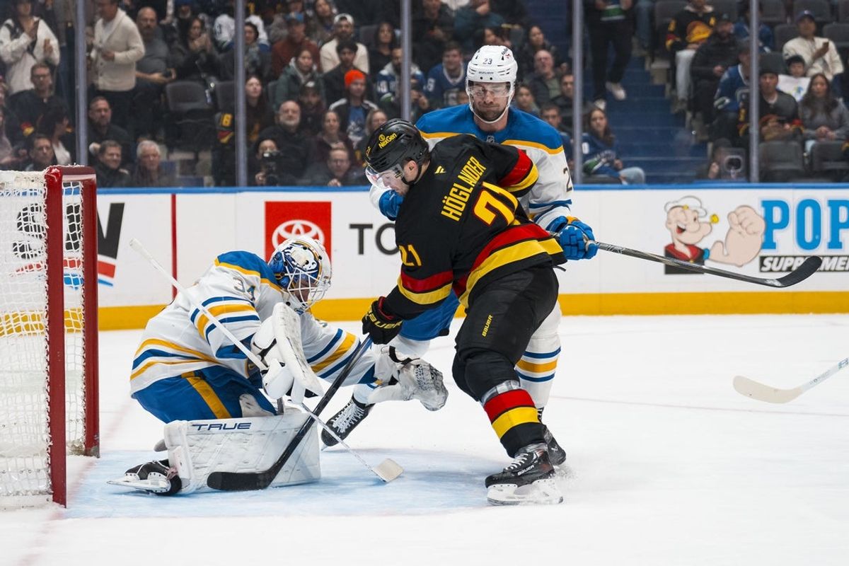 Dec 11, 2025; Vancouver, British Columbia, CAN; Buffalo Sabres defenseman Mattias Samuelsson (23) watches as goalie Alex Lyon (34) makes a save on Vancouver Canucks forward Nils Hoglander (21) in the first period at Rogers Arena. Mandatory Credit: Bob Frid-Imagn Images